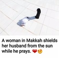 A women in Makkah shields hser husband from the sun while he prays